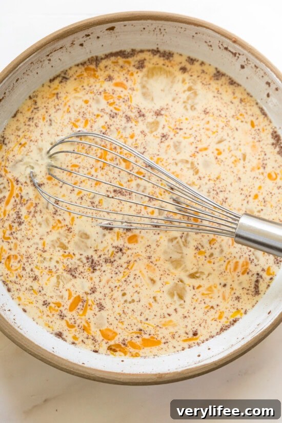 Egg custard in a bowl with a whisk.