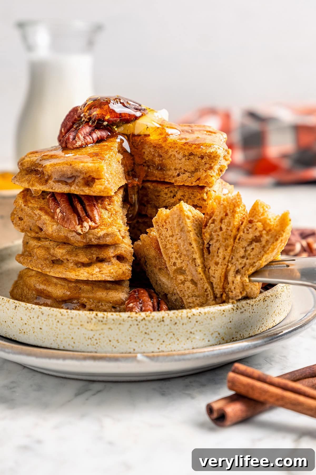 Fork piercing stack of fluffy pumpkin pancakes on plate