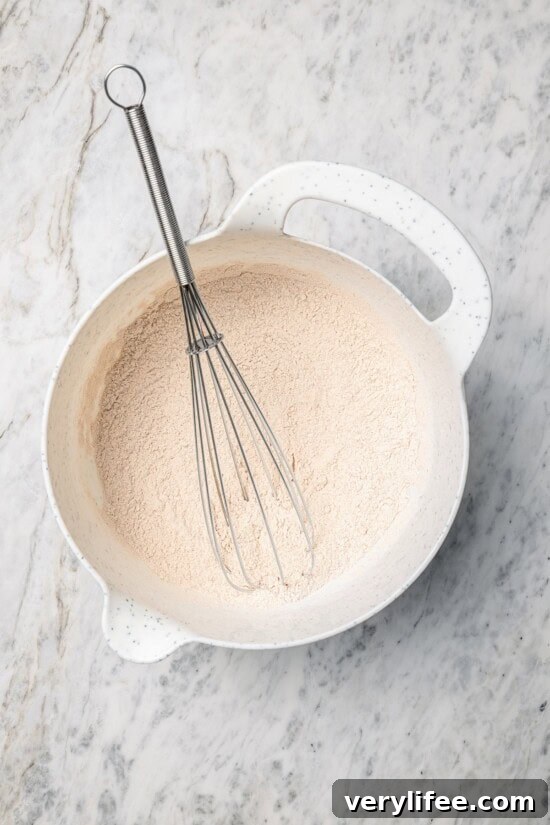 Overhead view of dry ingredients for pancakes in bowl with whisk