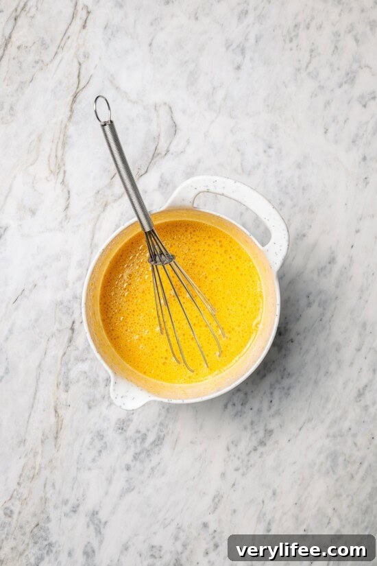Overhead view of wet ingredients in mixing bowl with whisk