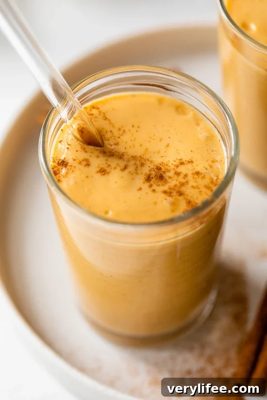 A pumpkin pie smoothie in a glass with a straw