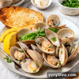 Tender Steamed Clams with Garlic and White Wine 11 Plate of steamed clams with basil, lemon wedges, and toast.