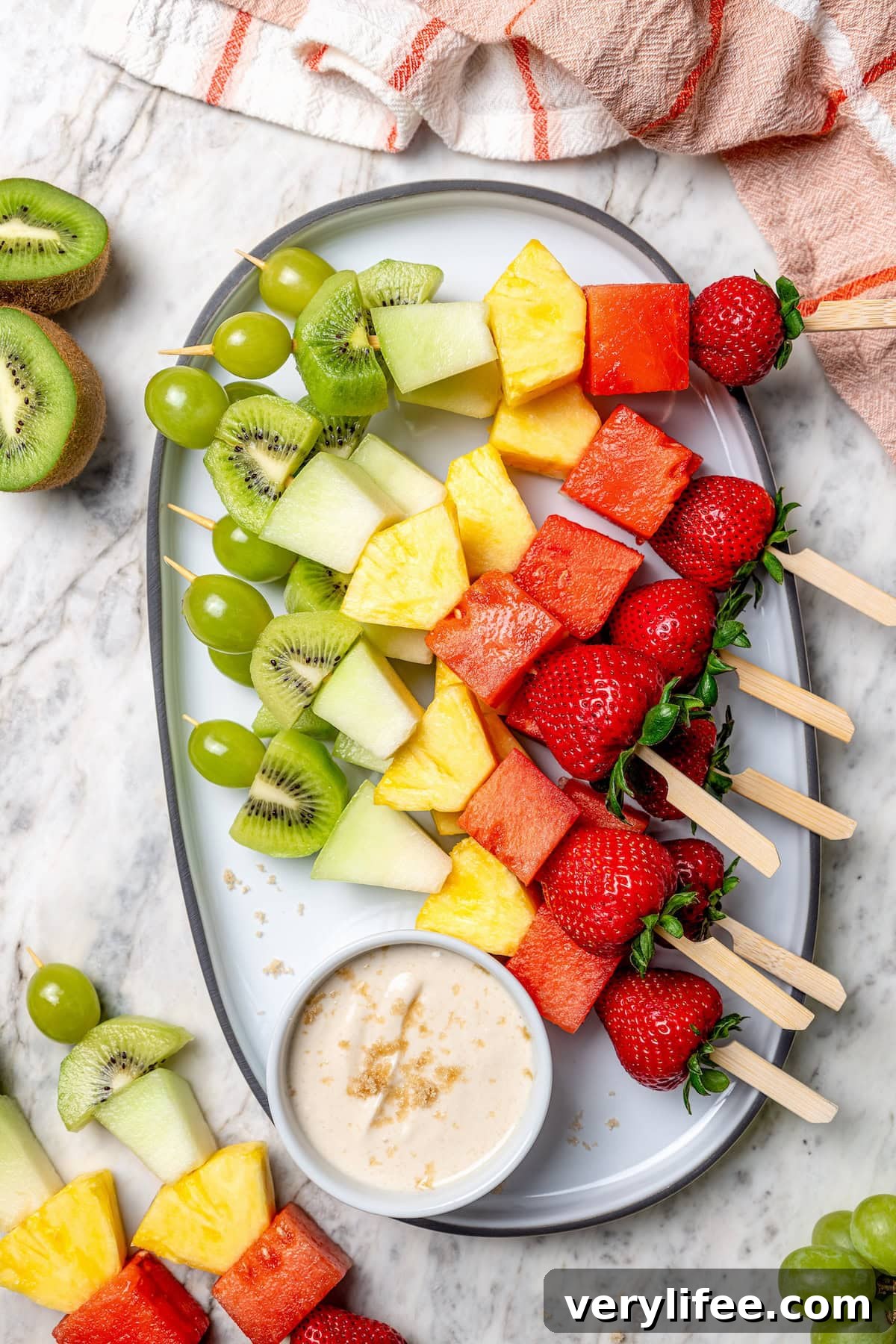 Rainbow fruit kabobs on platter with dip
