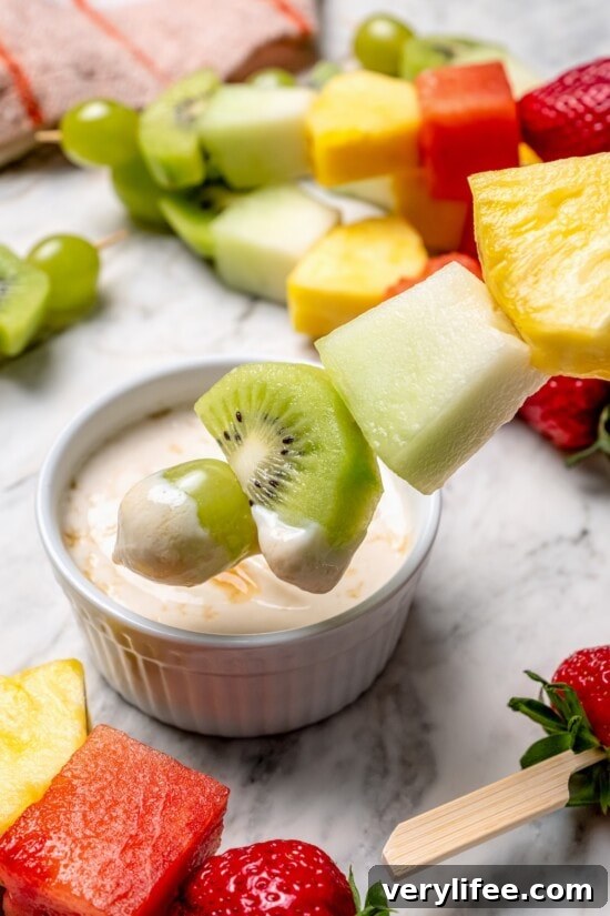 Dipping fruit kabob in bowl of dip