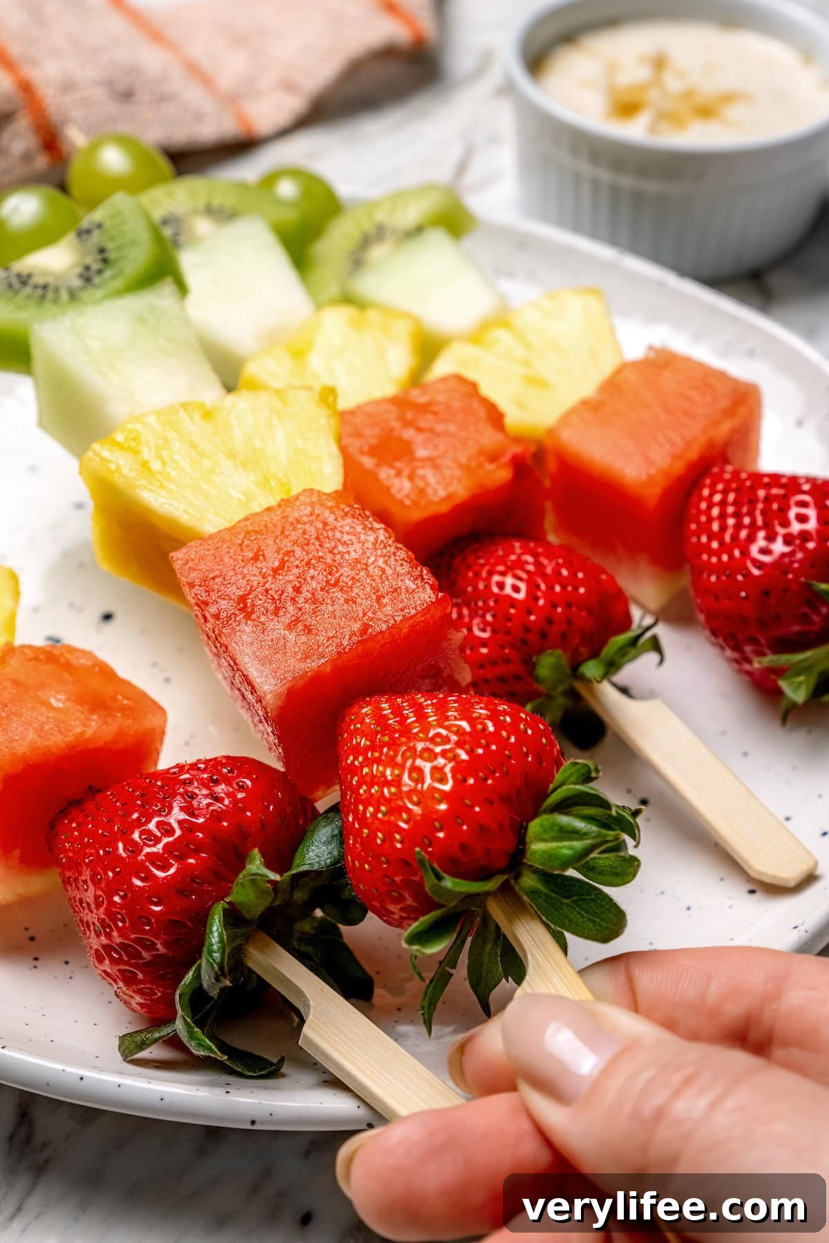 Hand holding fruit kabob on wooden skewer