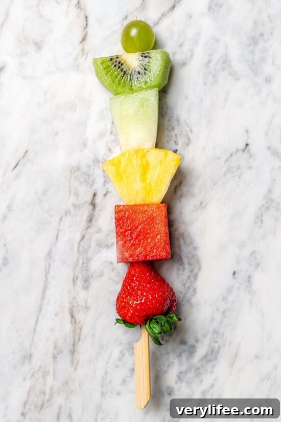Overhead view of single fruit skewer on marble countertop