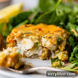 Baked Lump Crab Cakes with Chipotle-Lime Red Pepper Sauce 4 One half of a baked crab cake next to a fork on a plate, with a green salad in the background.