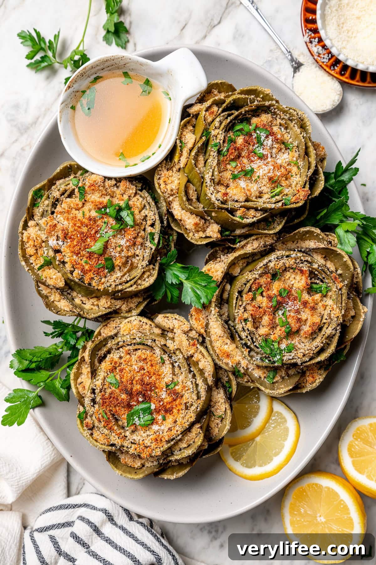 Garlic-Parmesan Stuffed Artichokes Recipe 7 Overhead view of stuffed artichokes on platter with lemon wheels