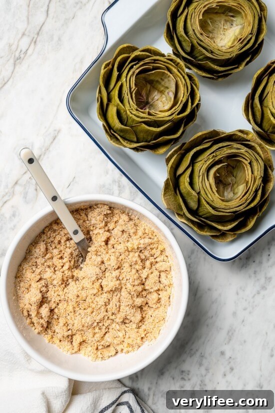 Garlic-Parmesan Stuffed Artichokes Recipe 5 Overhead view of artichokes in baking dish and breadcrumb mixture in bowl
