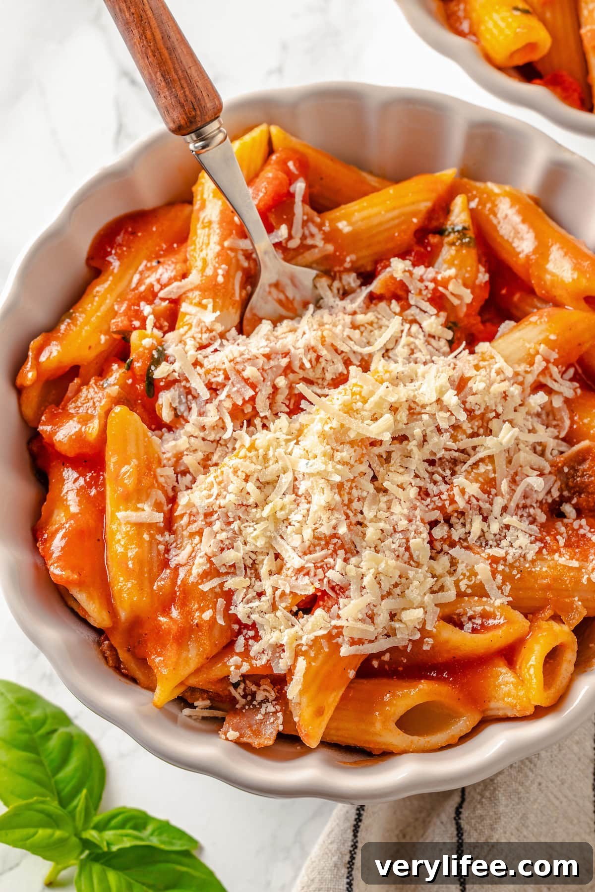 A bowl of penne alla vodka topped with grated cheese