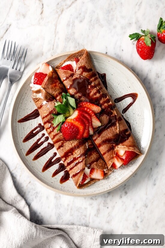 Plate of chocolate crepes with Cool Whip and strawberries.