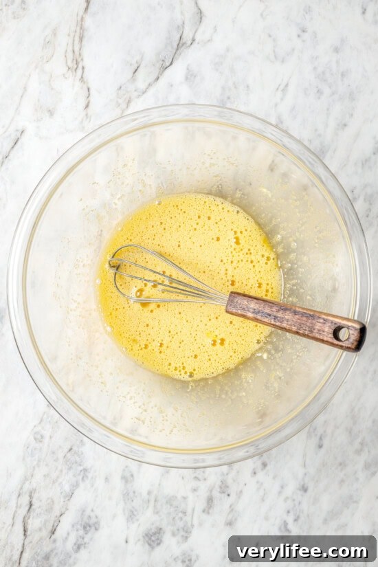 Egg and sugar mixture in bowl with whisk