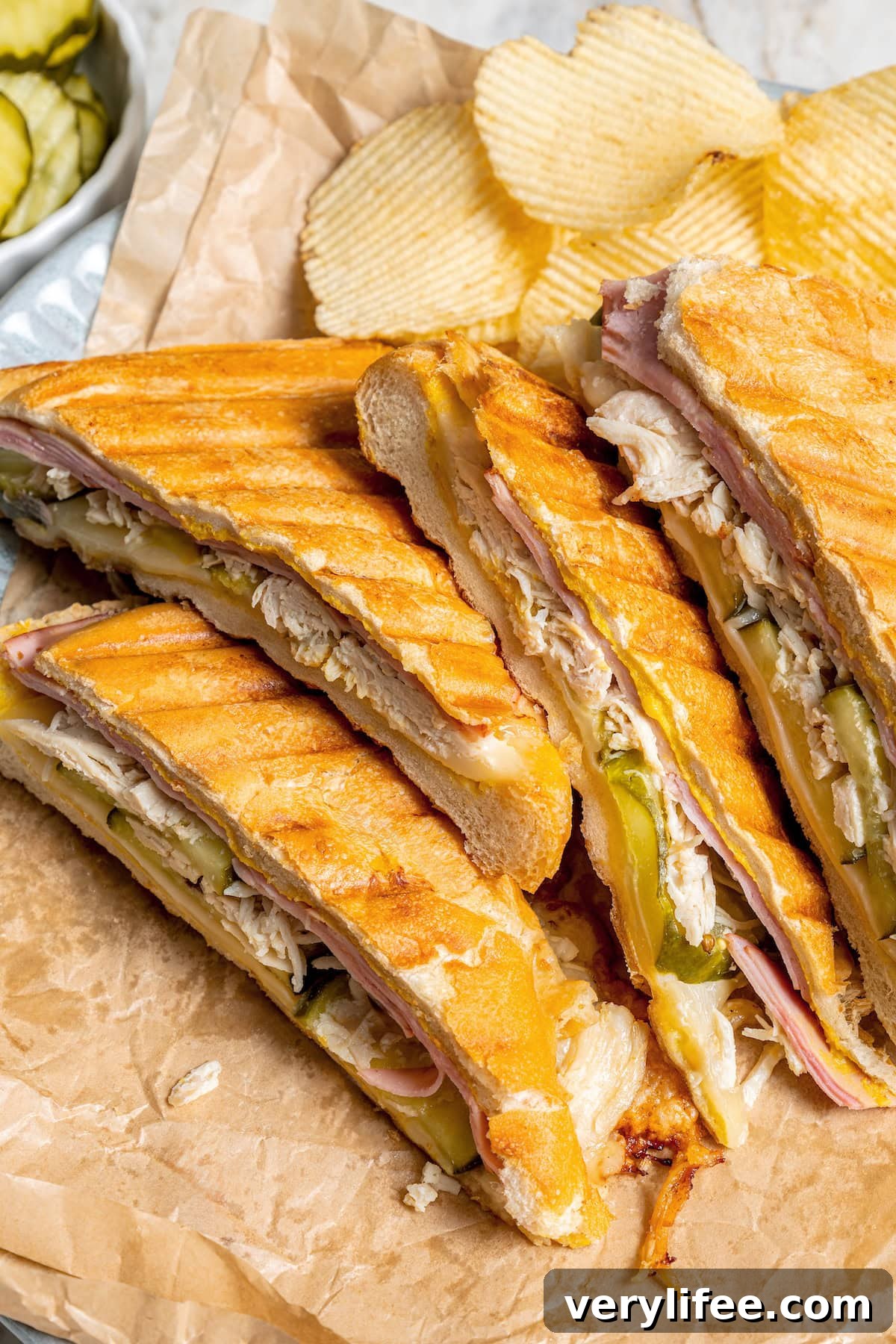4 turkey Cuban sandwiches on parchment paper with chips