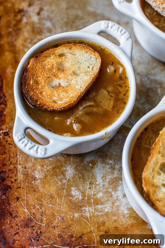 French onion soup topped with a slice of toasted bread in a ramekin.