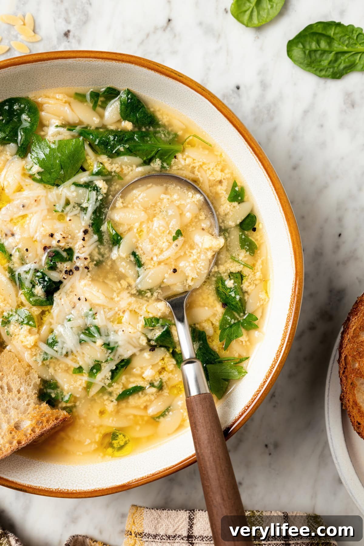 Classic Italian Stracciatella Soup with Spinach and Orzo 10 Spoonful of stracciatella soup in bowl.