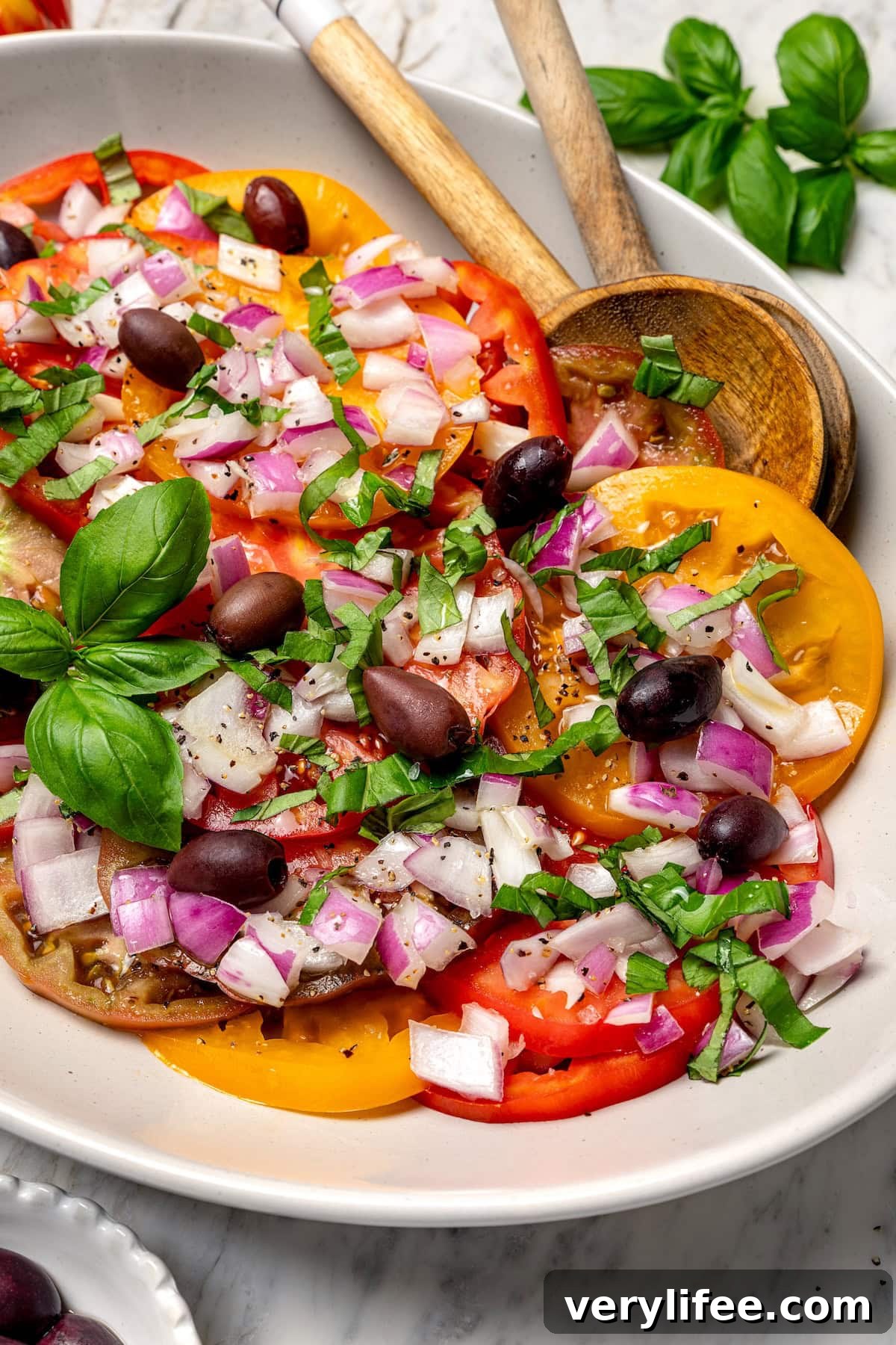 Heirloom tomato salad on platter with olives and onions