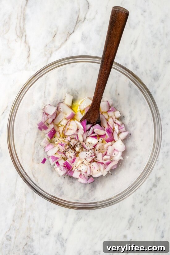Overhead view of onions in bowl with olive oil, salt, and pepper