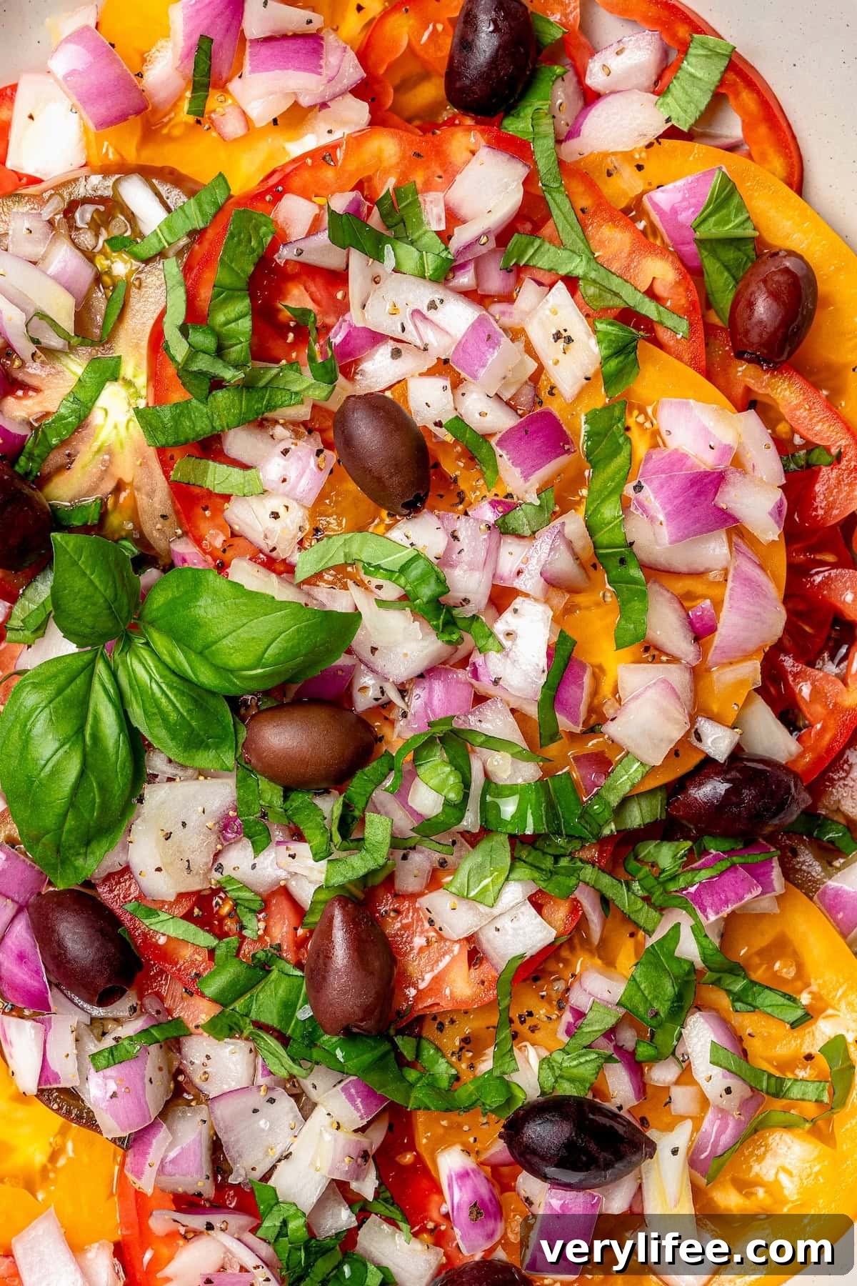 Overhead view of heirloom tomato salad with kalamata olives, basil, and red onion