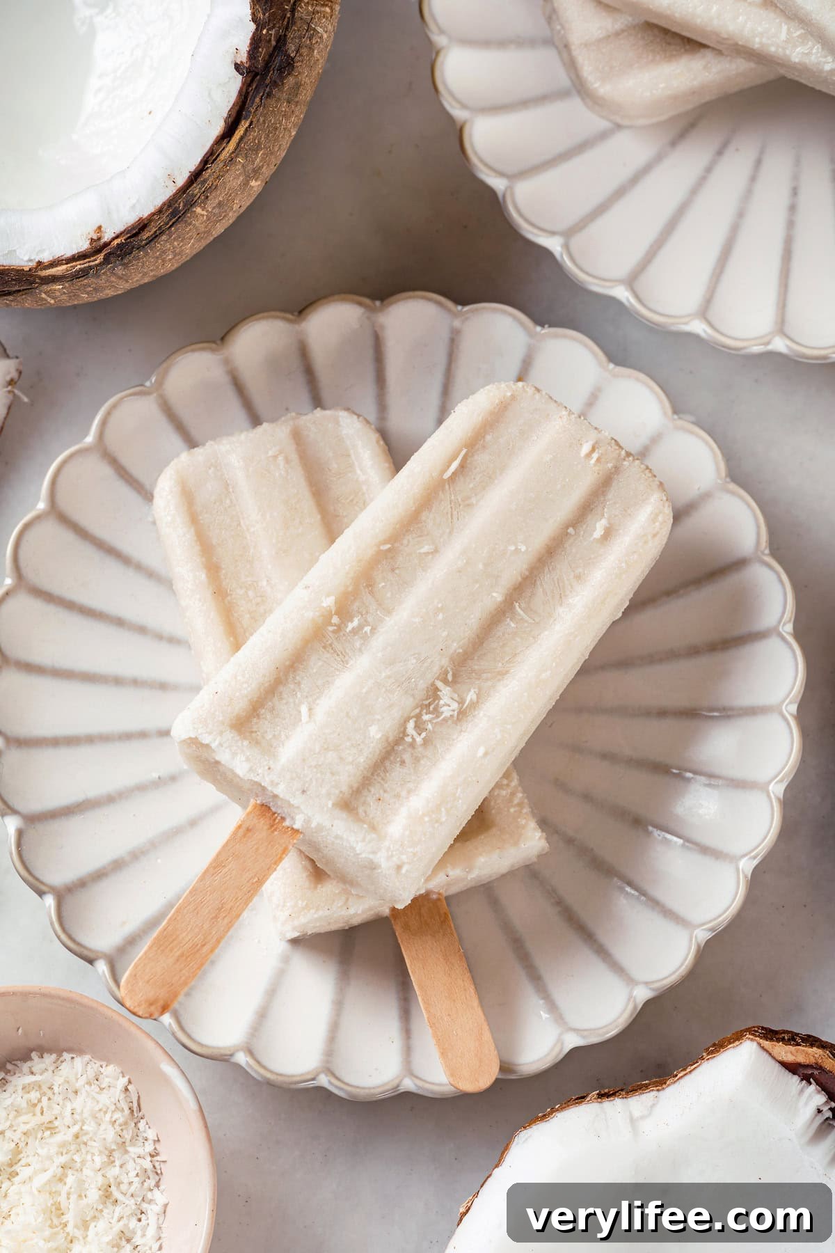 Two coconut popsicles on a plate. Two coconut popsicles set on plate