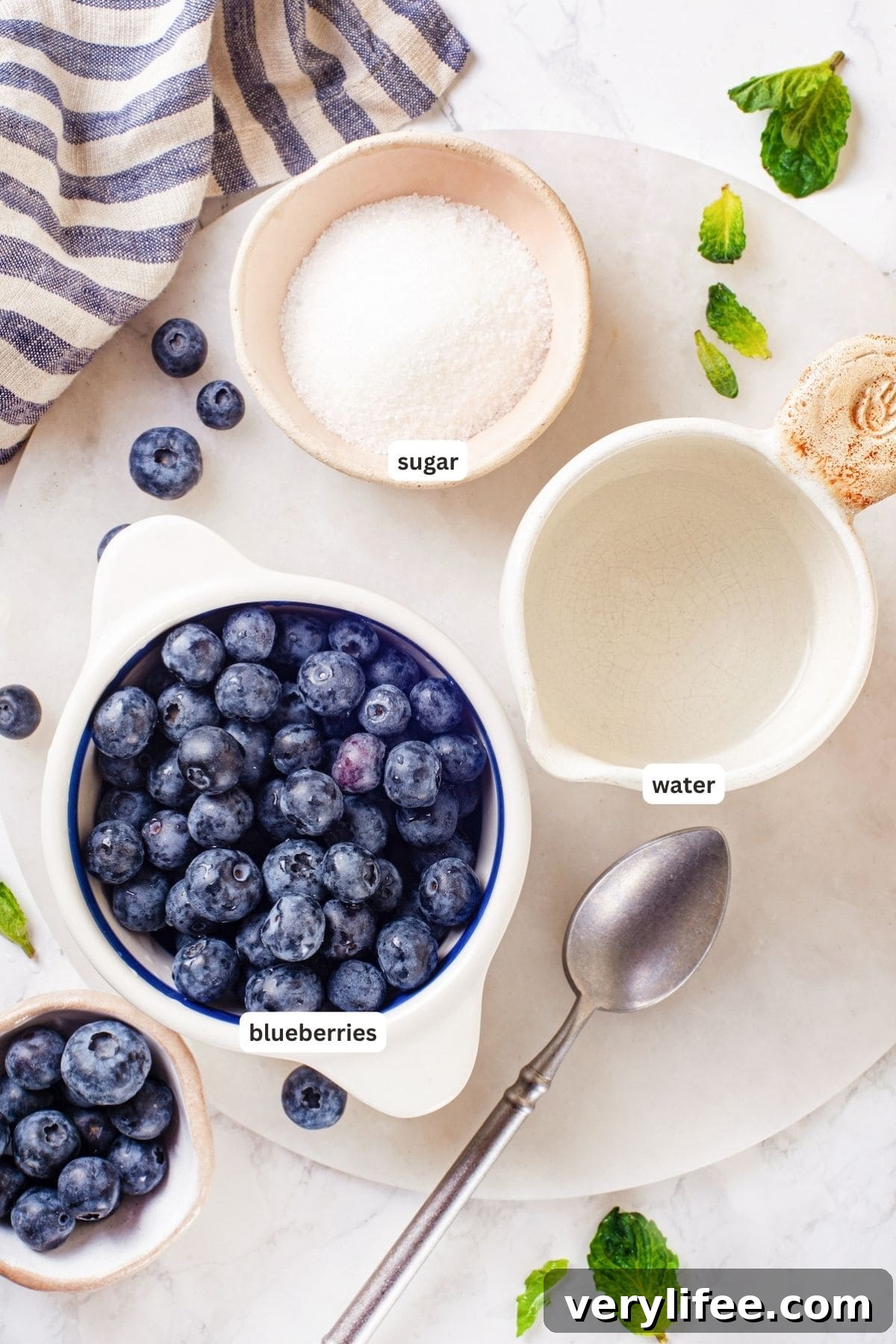 This easy blueberry compote recipe is a 3-ingredient fruit topping perfect for serving over ice cream, yogurt, and more. So summery! Overhead view of ingredients for blueberry compote with labels