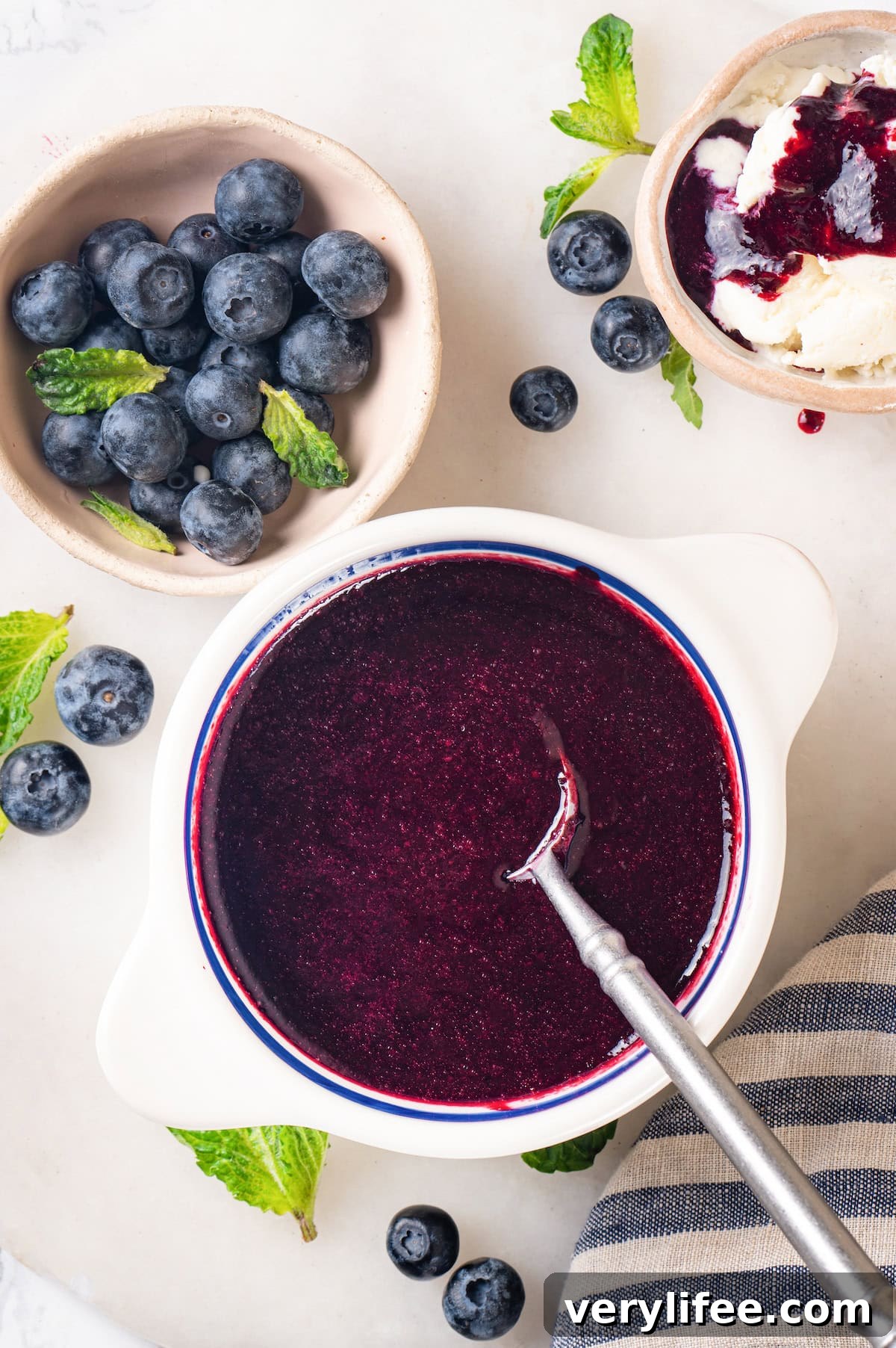 Blueberry compote ready to spoon over yogurt, ice cream, and more. Overhead view of blueberry compote in bowl with spoon
