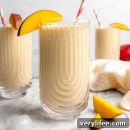 3 homemade mango lassis in glasses with mango slices on rim for garnish