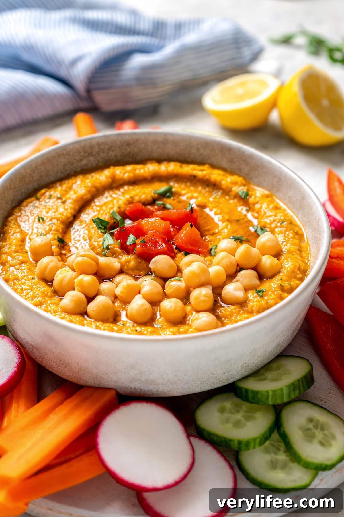 Bowl of roasted red bell pepper hummus garnished with peppers and chickpeas