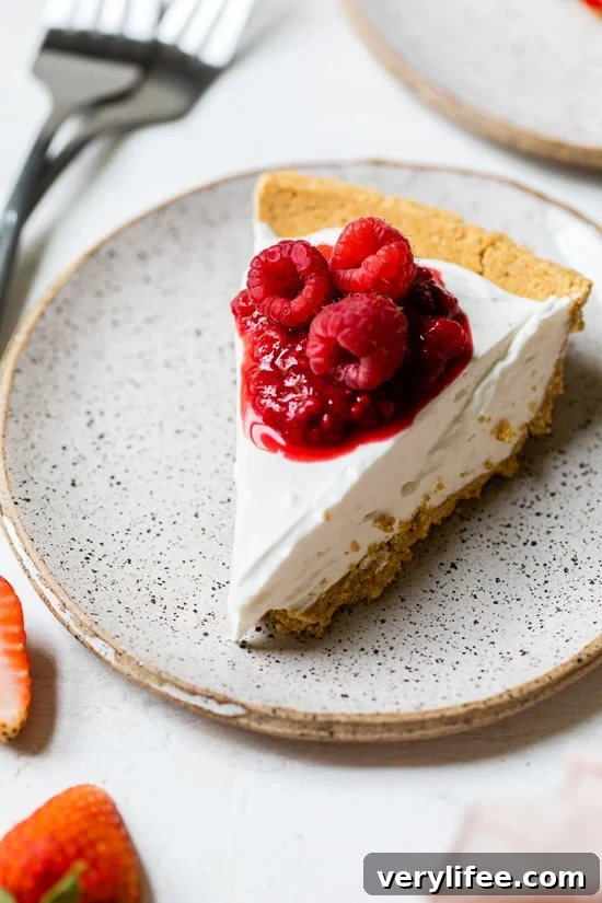 No-Bake Cheesecake Recipe Slice of no-bake cheesecake on plate with macerated and fresh raspberries on top
