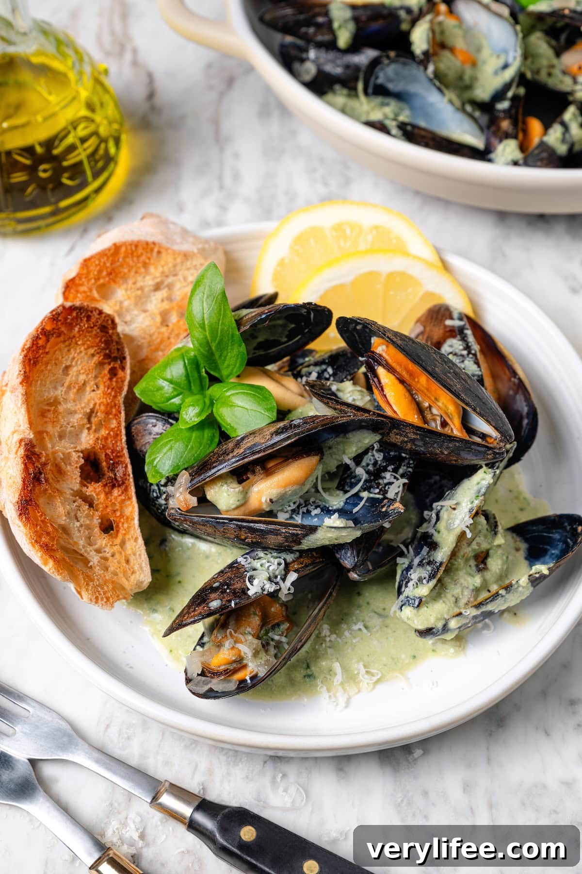 With tender mussels in cream sauce with Parmesan and basil, this recipe is perfect for special occasions, but easy enough for a weeknight! Plate of mussels with basil cream sauce and toast.