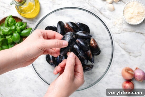Creamy Basil Mussels Recipe 5 Hand holding mussel over bowl.