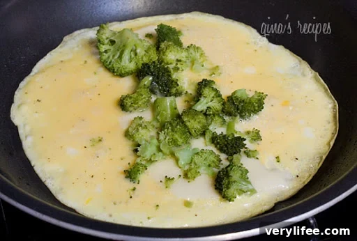 Broccoli and Cheddar Omelet Recipe 3 An open omelet with broccoli and cheese in a skillet