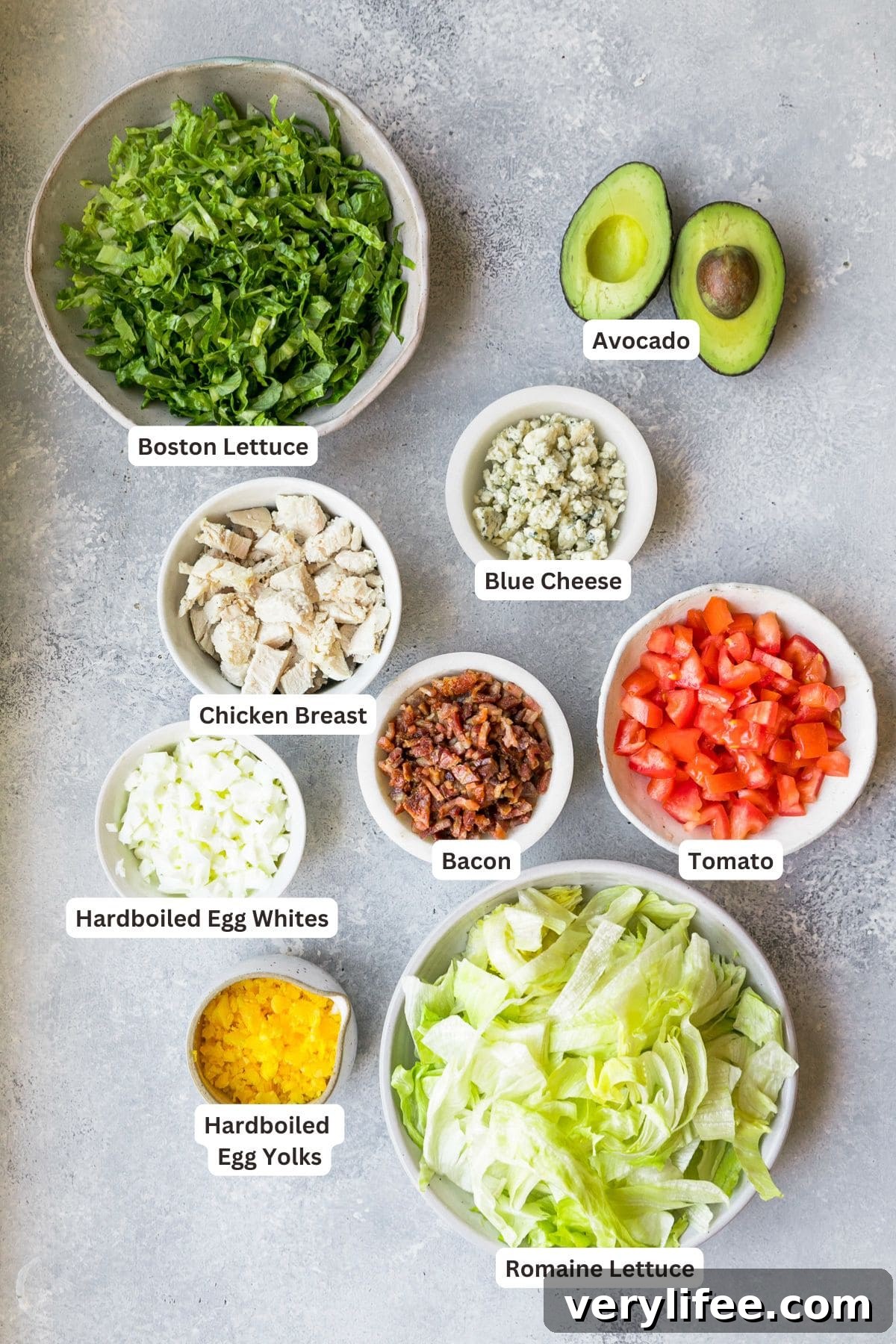 Classic Cobb Salad Recipe with Avocado and Bacon 2 Ingredients for cobb salad in white bowls on a marble background.