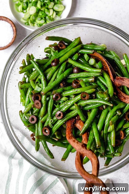 Green beans and olives in bowl with salad tongs.