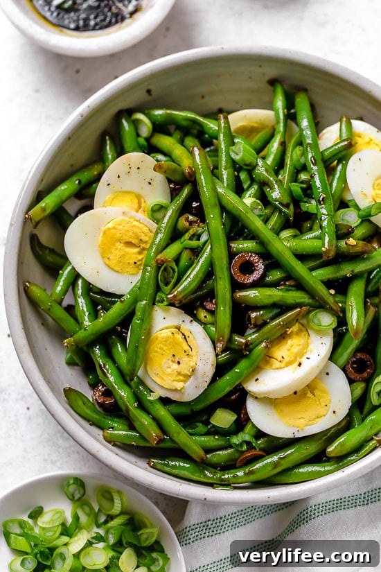 Bowl of green bean salad with olives and eggs.