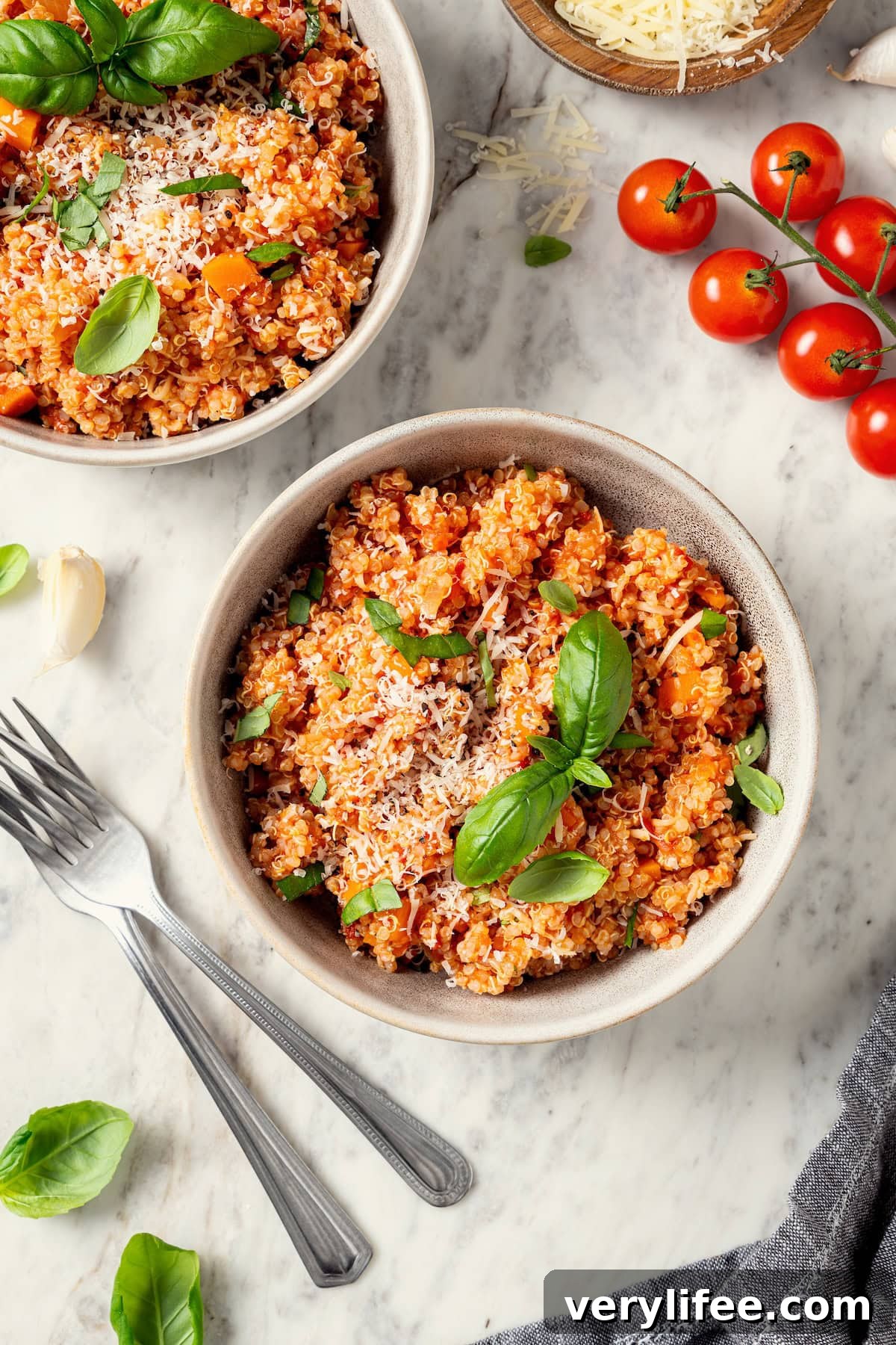 Two bowls of quinoa risotto with cheese and fresh basil.