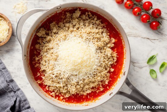 Cheese and quinoa added to skillet of tomato sauce.