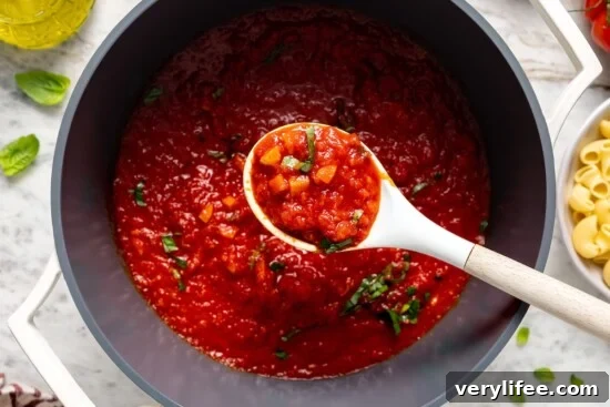 Spoonful of chunky filetto di pomodoro sauce held over pot.