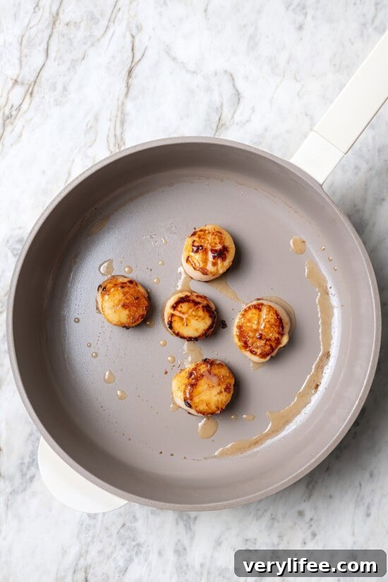 Overhead view of scallops searing in pan