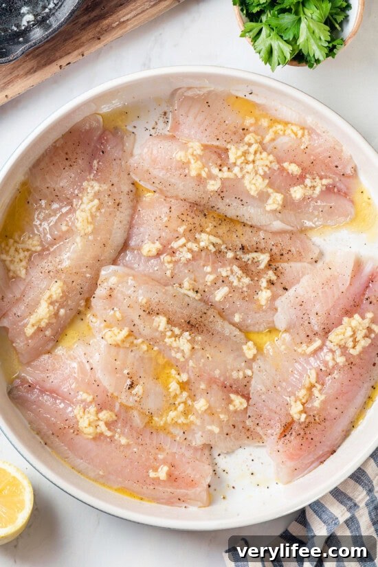 Crispy Oven Baked Tilapia with Lemon and Herbs 4 Overhead view of tilapia fillets in pan before baking