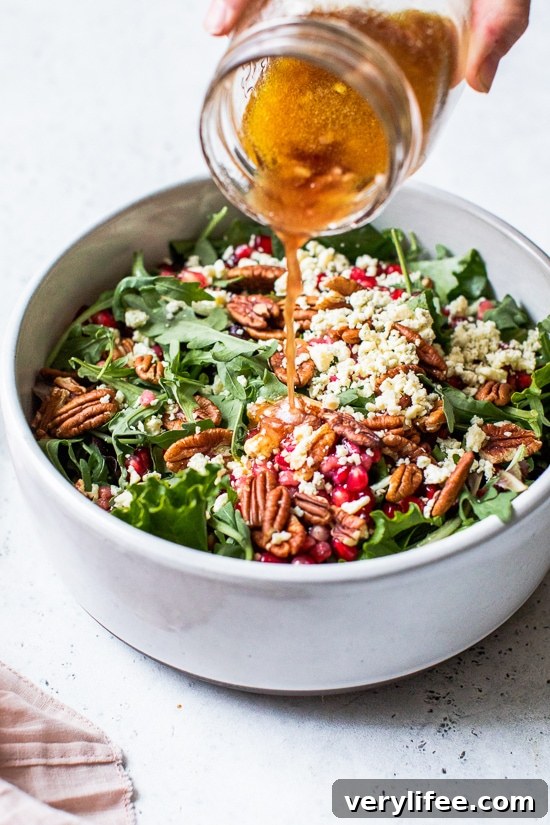 Pouring pomegranate vinaigrette over salad.