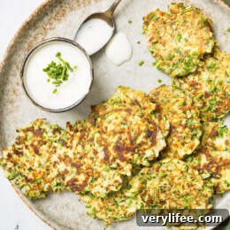 Zucchini pancakes next to dipping sauce on a plate.