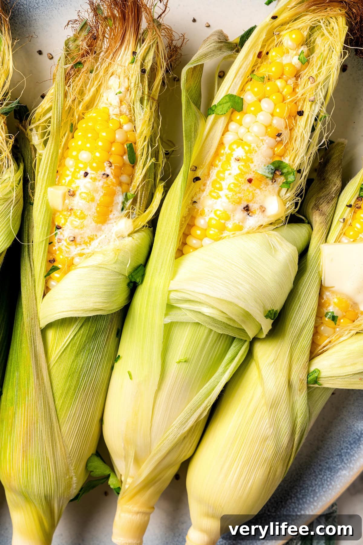 Once you try this microwave corn on the cob recipe, you may never go back to boiling! It's quick, easy, and cleanup is a breeze. Peeling away husk from microwave corn on the cob.