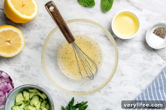 Lemon dressing in bowl with small whisk.