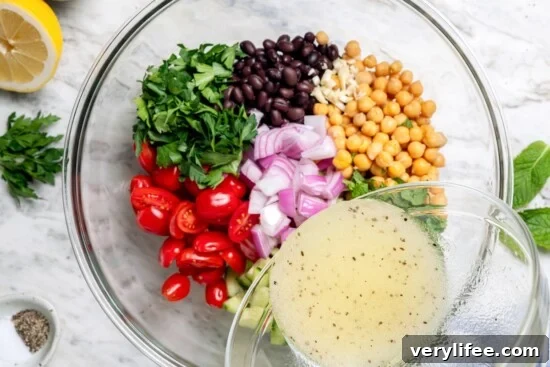 Pouring lemon dressing into bowl with bean salad ingredients.