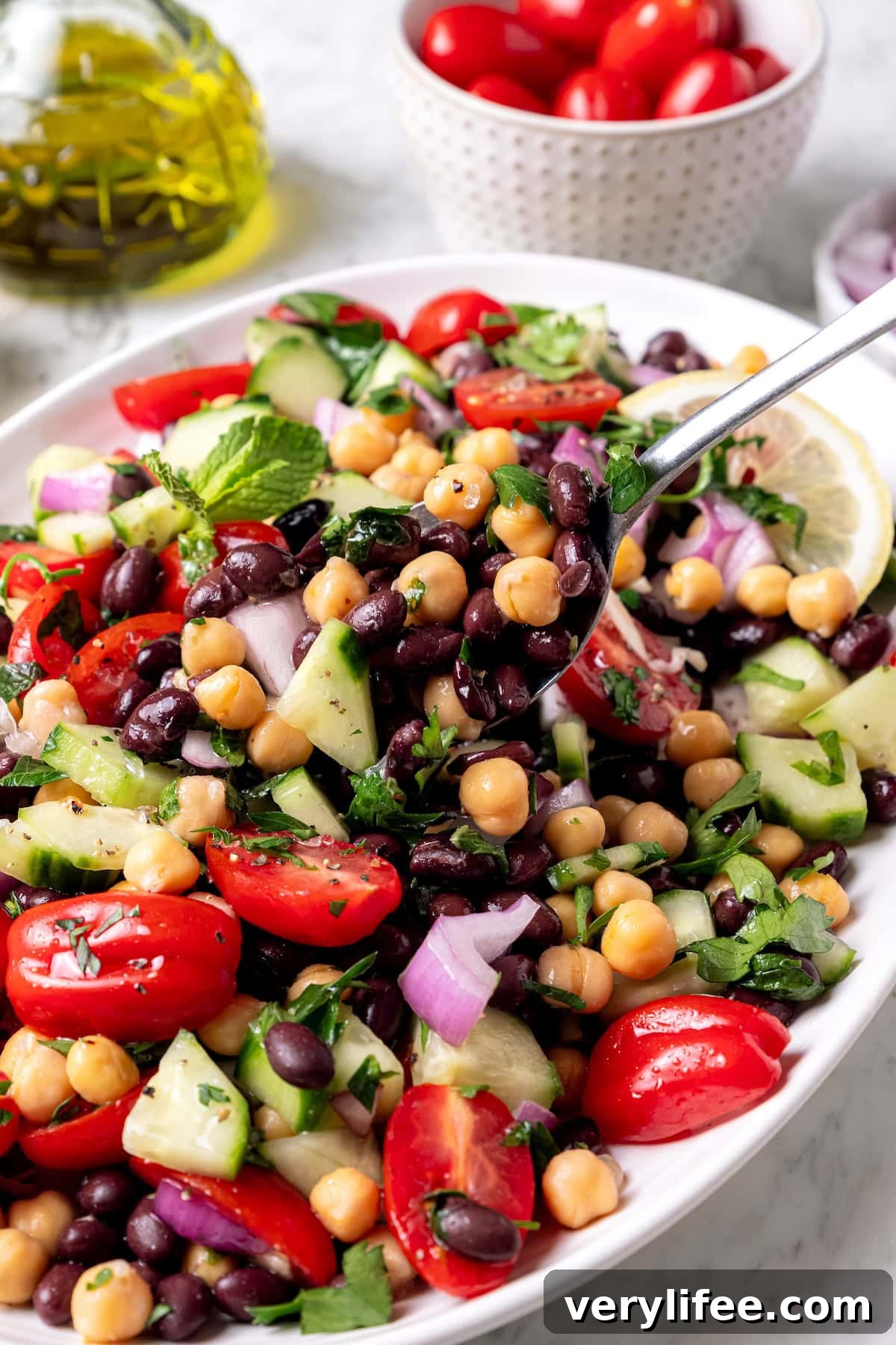 Garbanzo bean Mediterranean salad in serving spoon held over bowl.