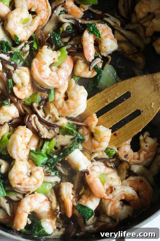 garlicky shrimp stir-fry with shiitakes and bok choy cooked in a pan.
