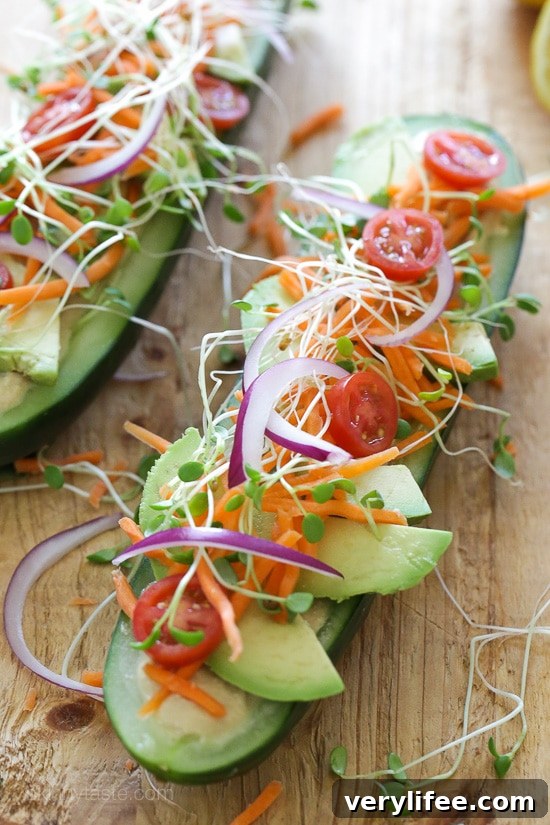 Cucumbers filled with hummus, avocado and fresh vegetables, photographed from above.