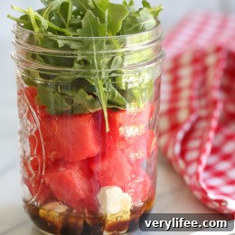 Prepared jarred watermelon feta arugula salads ready to take on a picnic.