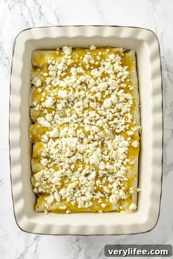 Queso fresco on top of salsa verde on enchiladas