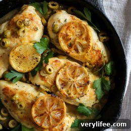Chicken breasts cooked in a skillet with green olives, lemon and fresh herbs.